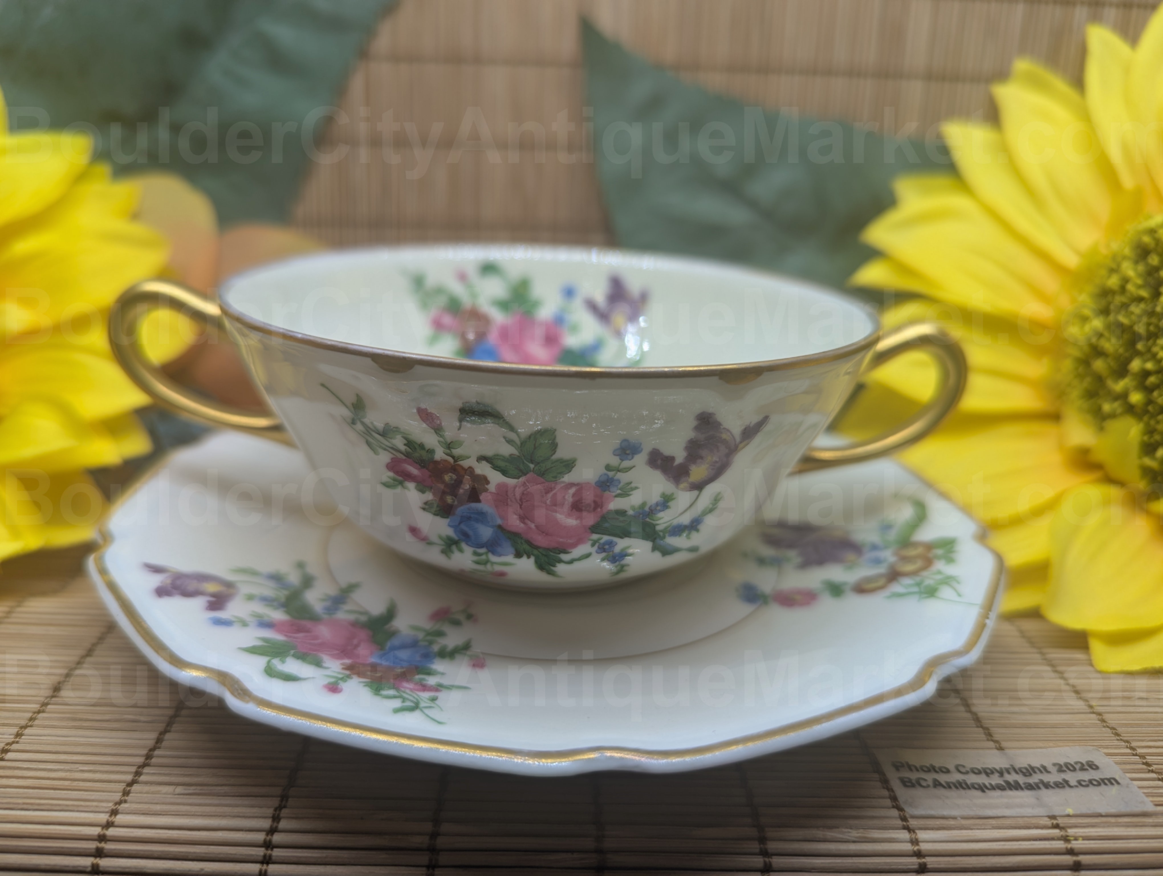 Tressemanes & Vogt Limoges porcelain consommé cup and saucer. This T&V set was decorated for the W.H. Plummer & Co retailer at 7 East 35th Street in New York, New York. The W.H. Plummer & Co, Ltd, imported fine china from European sources in the 1890s to the 1950s. This rose and floral design is French, the cup is 4 3/8 inches in diameter with multiple gold designs on the handles, rim, inside and foot of the cup with floral designs both inside and on the outside of the cup. The saucer is six inches in diameter with square scalloped edges enhanced by gold edge and inner gold lines. The set is two toned in white and cream and dates from the earlier years of the import company prior to 1940.